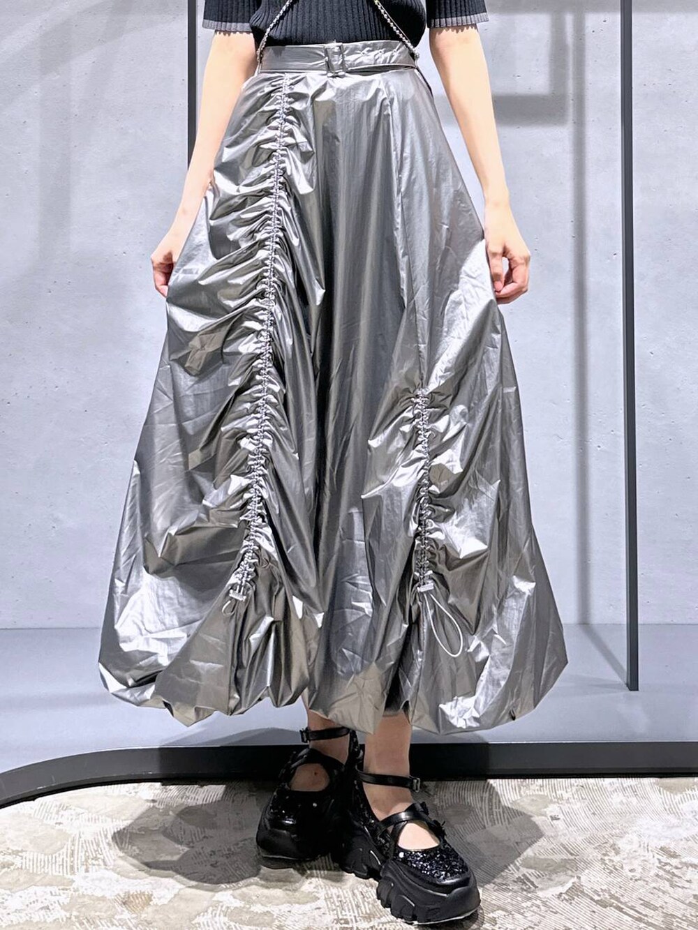 ブラック系のニット/セーター、ブラック系のスニーカー、シルバー系のスカートを着用したレディースの夏コーディネートの6枚目の写真