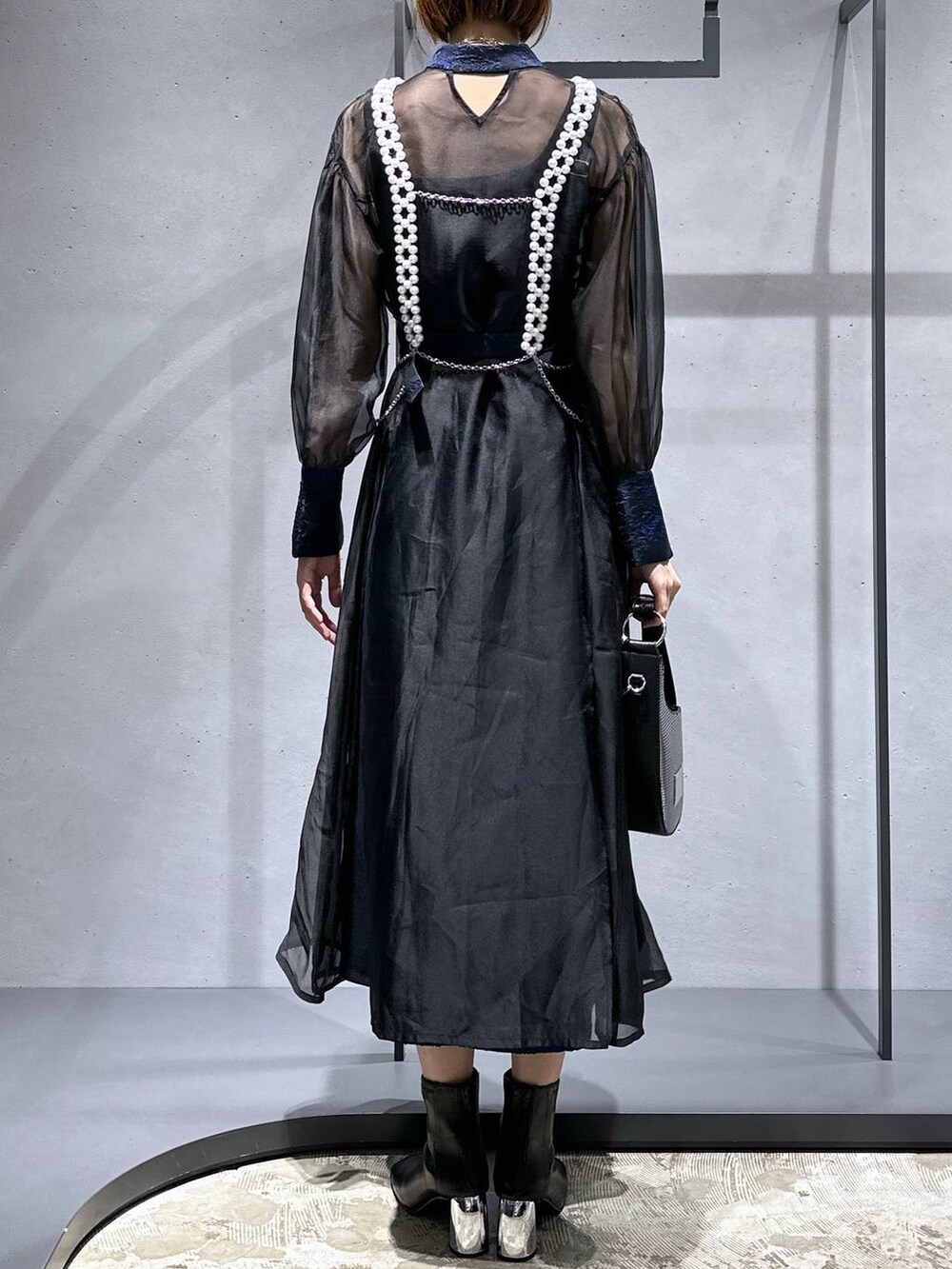 シルバー系のハンドバッグ、ブラック系のブーツ、ブルー系のドレスを着用したレディースの秋コーディネートの3枚目の写真