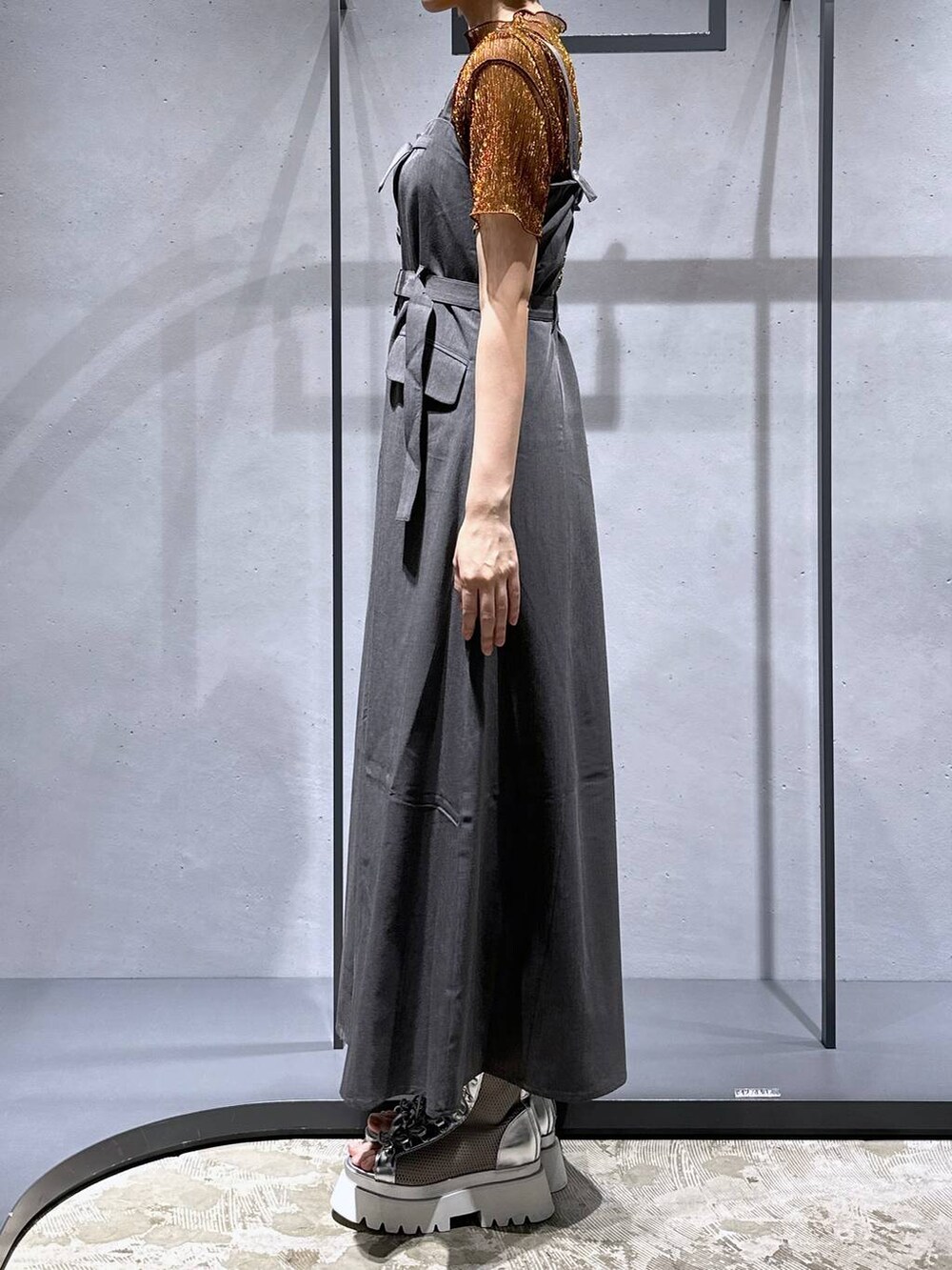 シルバー系のサンダル、オレンジ系のTシャツ/カットソー、グレー系のジャンパースカートを着用したレディースの夏コーディネートの4枚目の写真