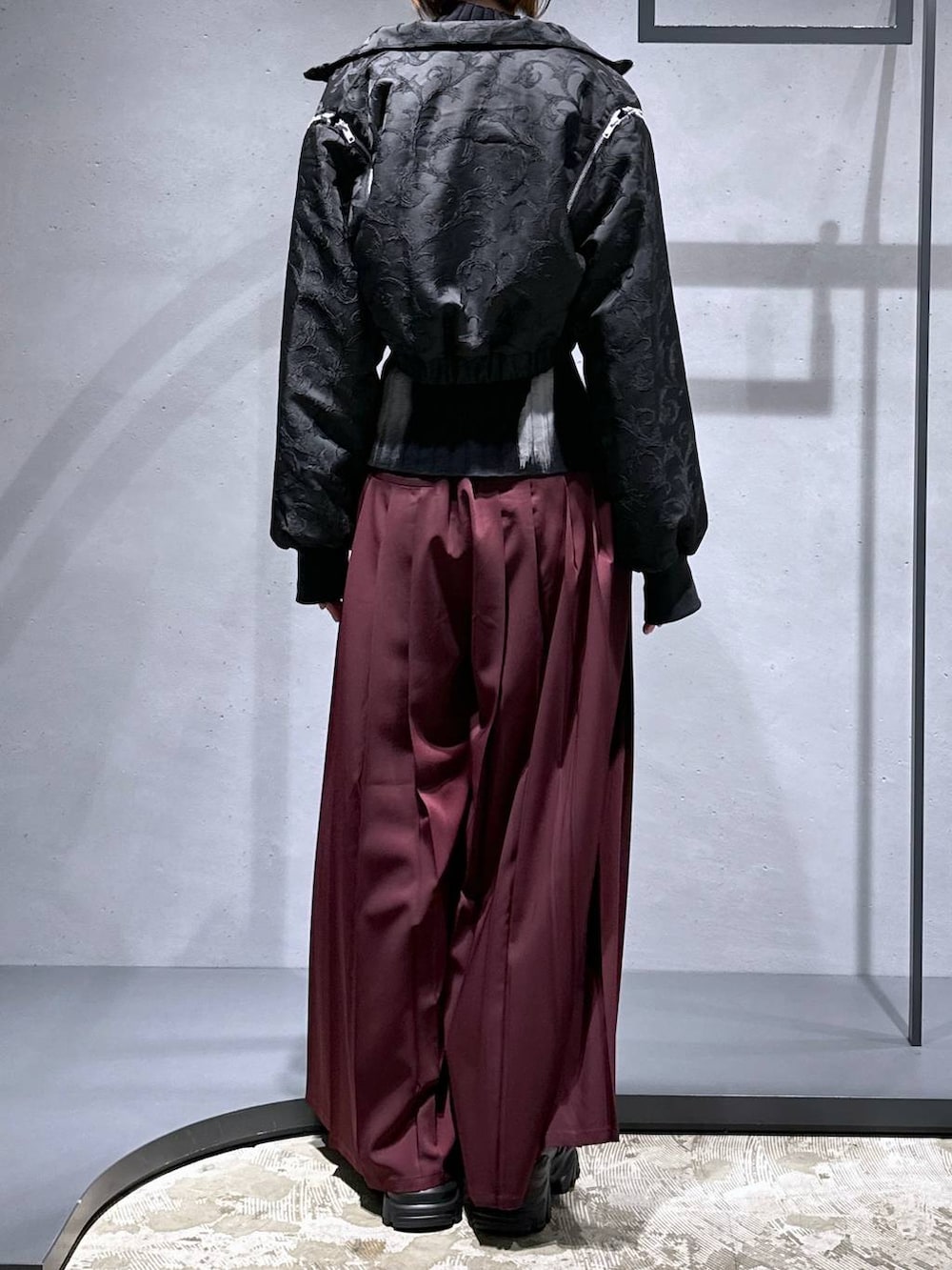 ブラック系のブルゾン、レッド系のその他パンツ、ブラック系のローファーを着用したレディースの秋コーディネートの3枚目の写真