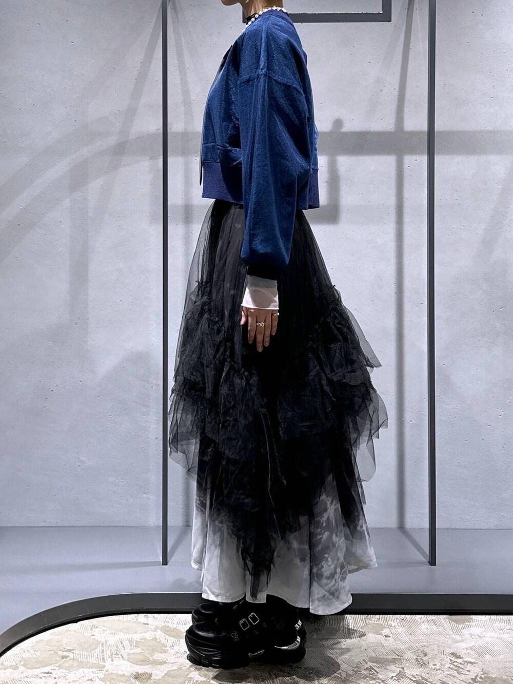 ブラック系のネクタイ、ブルー系のカーディガン/ボレロ、ブラック系のスカートを着用したレディースの冬コーディネートの2枚目の写真