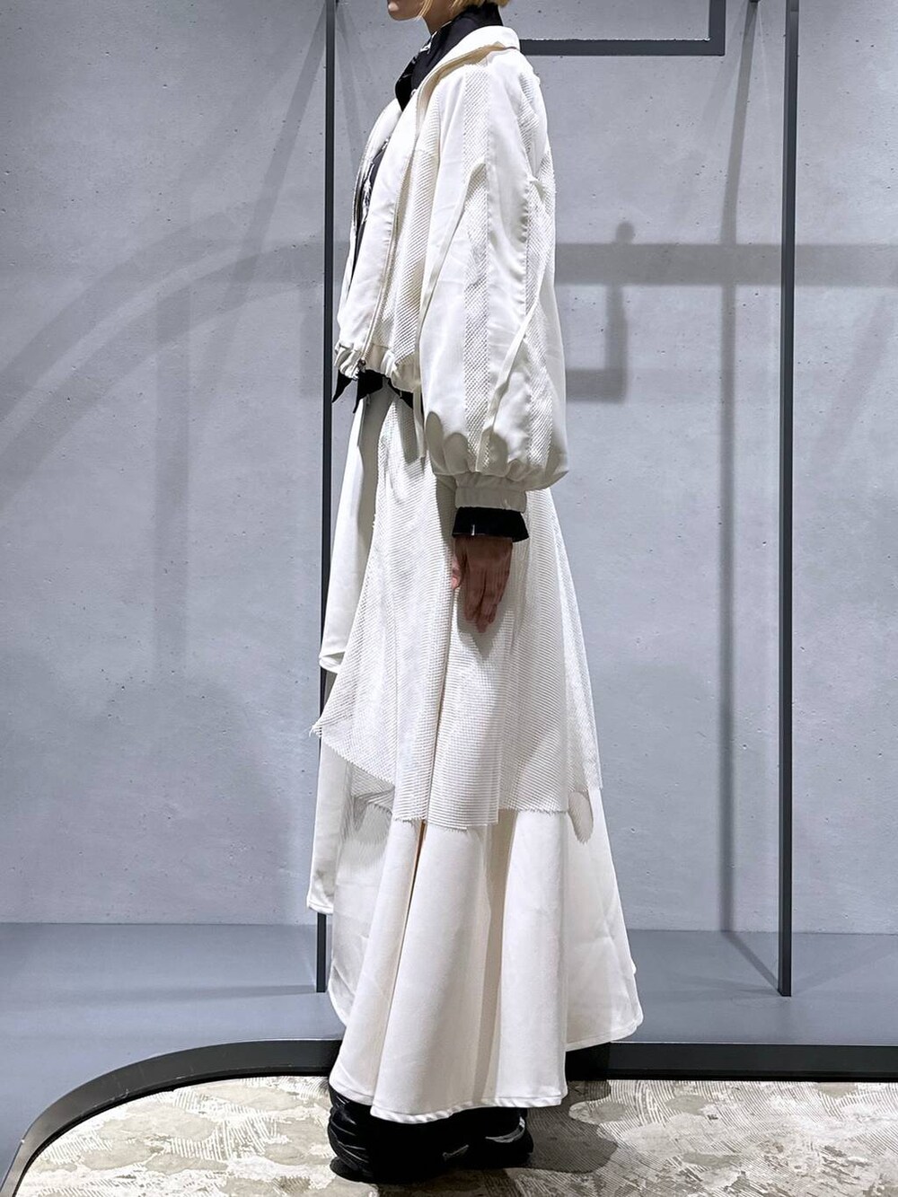 ブラック系のスニーカー、ホワイト系のブルゾン、ホワイト系のスカートを着用したレディースの冬コーディネートの2枚目の写真