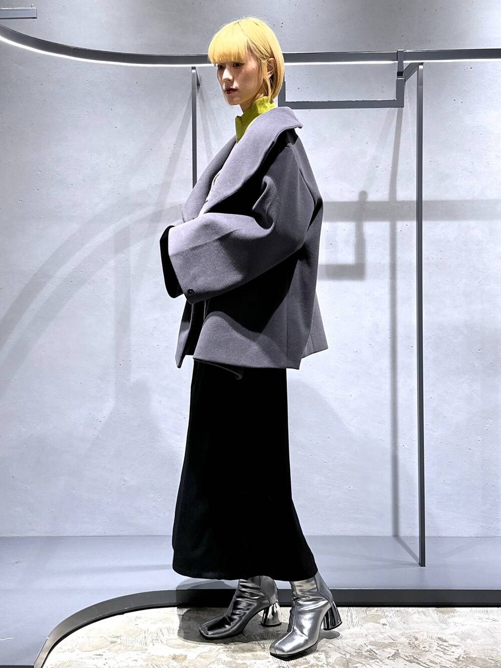 グレー系のチェスターコート、イエロー系のニット/セーター、シルバー系のブーツを着用したレディースの秋コーディネートの4枚目の写真