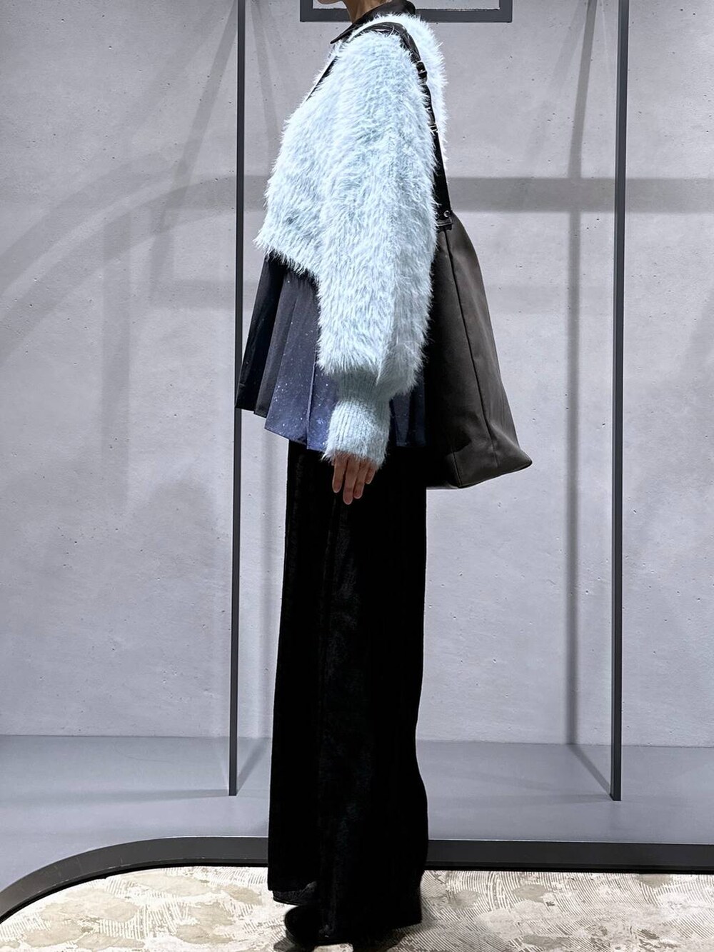 グリーン系のニット/セーター、ブラック系のブーツ、ブルー系のシャツ/ブラウスを着用したレディースの冬コーディネートの2枚目の写真