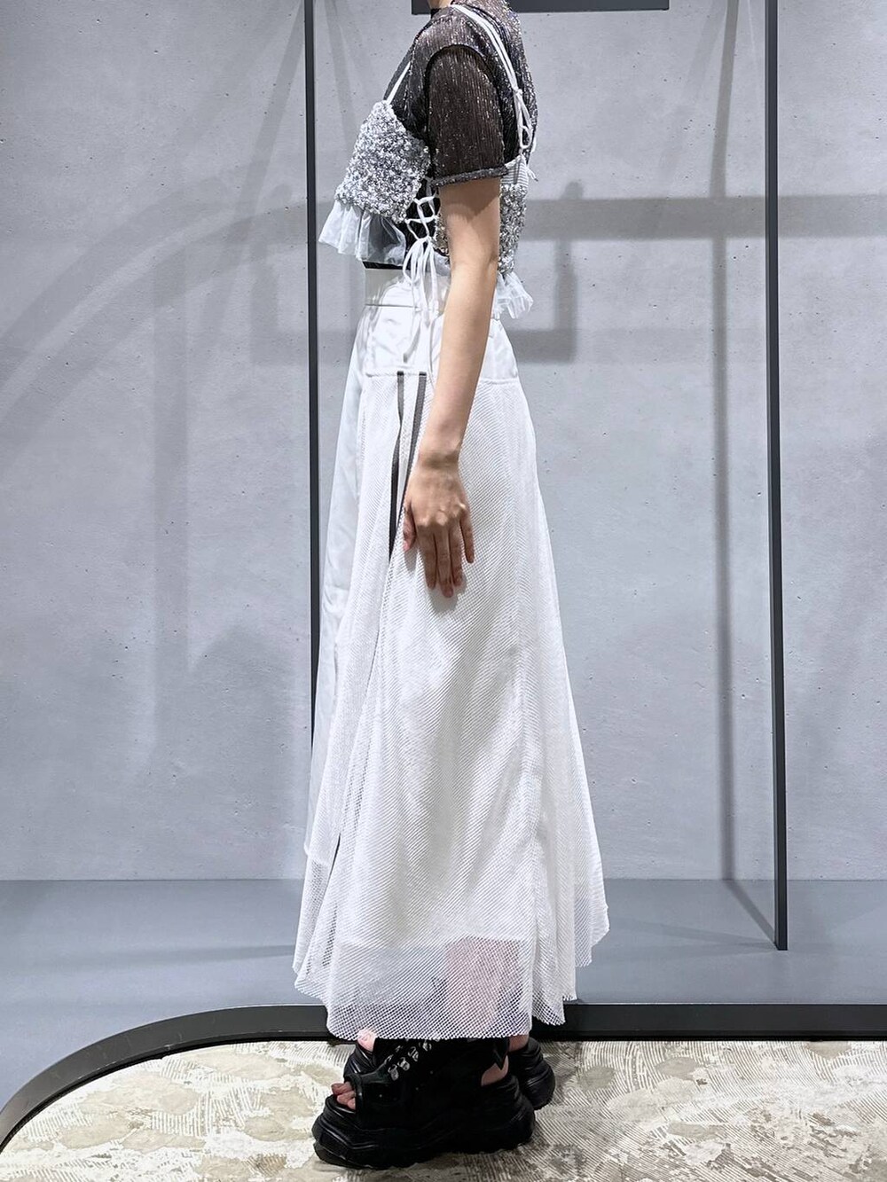 シルバー系のチューブトップ、ブラック系のTシャツ/カットソー、ホワイト系のスカートを着用したレディースの夏コーディネートの2枚目の写真