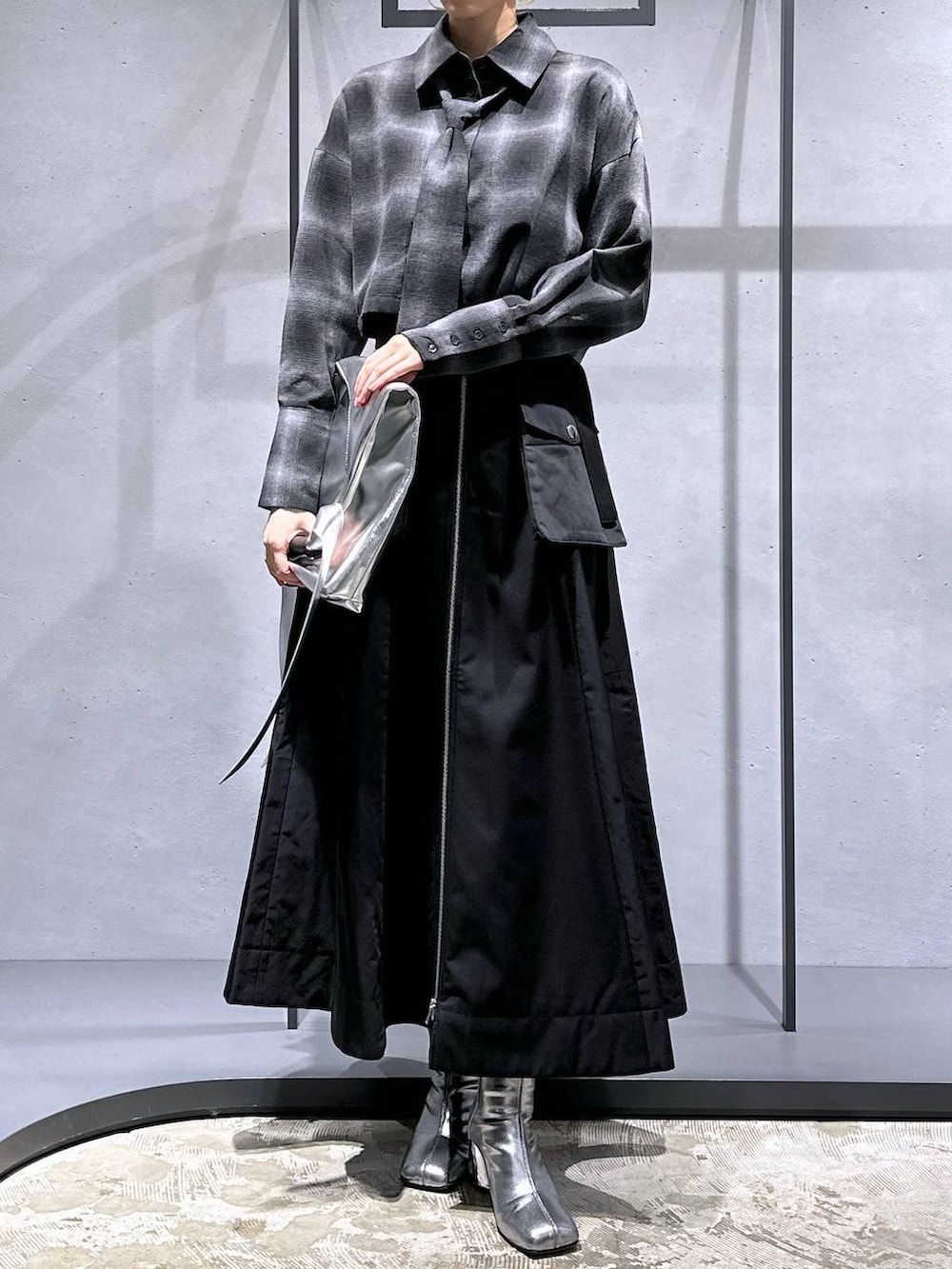 シルバー系のブーツ、ブラック系のスカート、シルバー系のトートバッグを着用したレディースの秋コーディネートの4枚目の写真