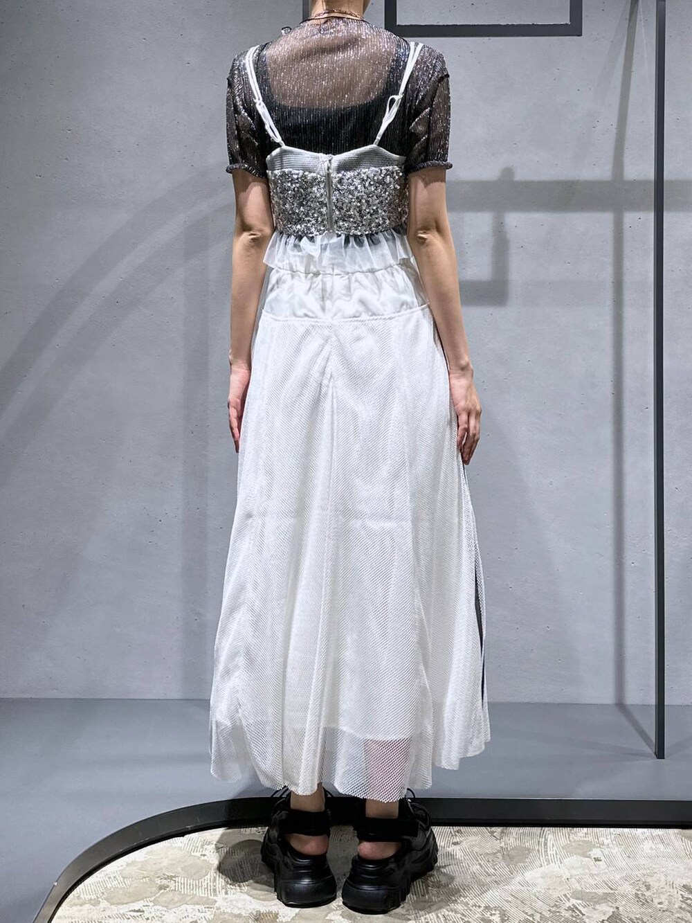 シルバー系のチューブトップ、ブラック系のTシャツ/カットソー、ホワイト系のスカートを着用したレディースの夏コーディネートの3枚目の写真