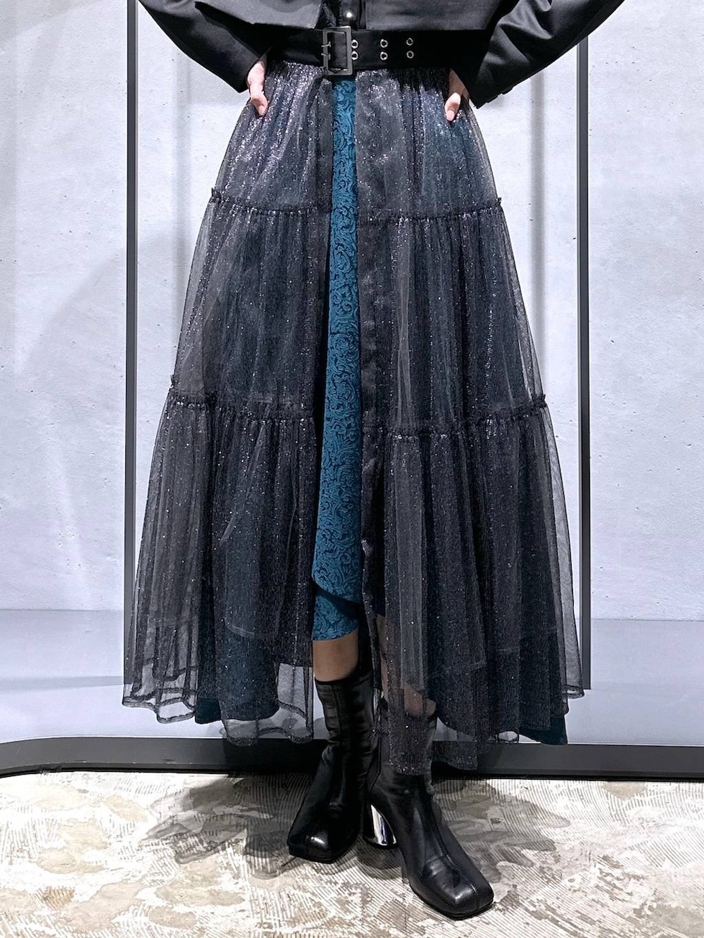 グリーン系のスカート、ブラック系のブーツ、ブラック系のシャツ/ブラウスを着用したレディースの秋コーディネートの6枚目の写真