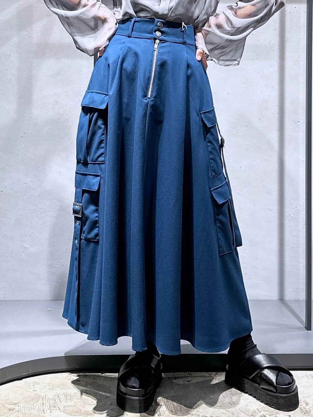 ブラック系のサンダル、ブルー系のスカート、シルバー系のネックレスを着用したレディースの春コーディネートの6枚目の写真