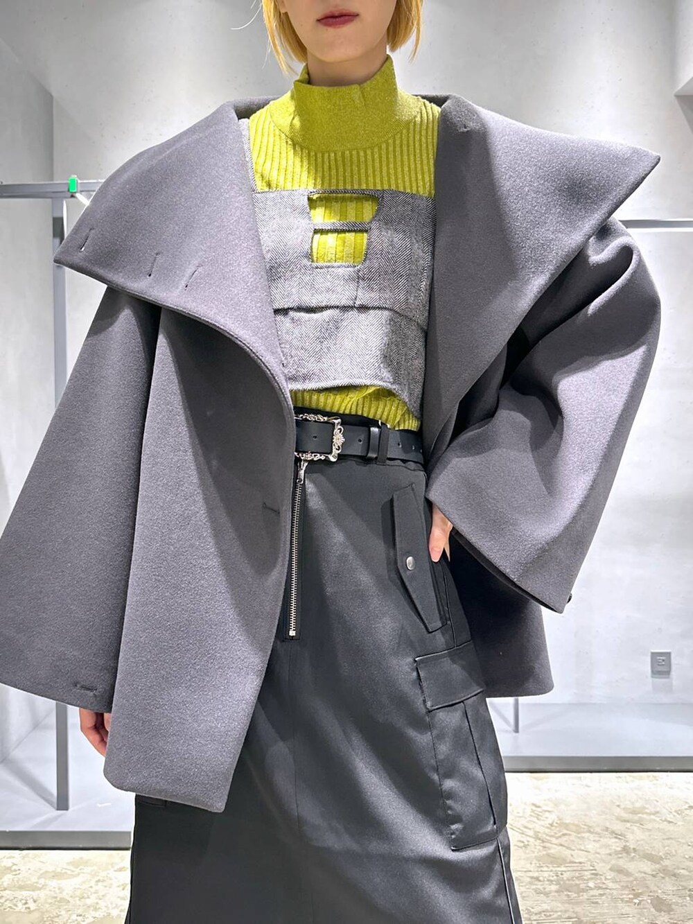 グレー系のチェスターコート、イエロー系のニット/セーター、シルバー系のブーツを着用したレディースの秋コーディネートの6枚目の写真