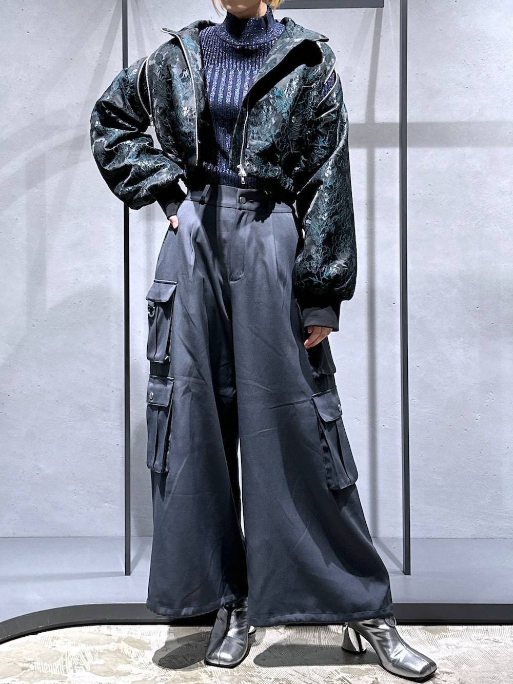 グリーン系のブルゾン、シルバー系のブーツ、ブルー系のニット/セーターを着用したレディースの秋コーディネートの4枚目の写真