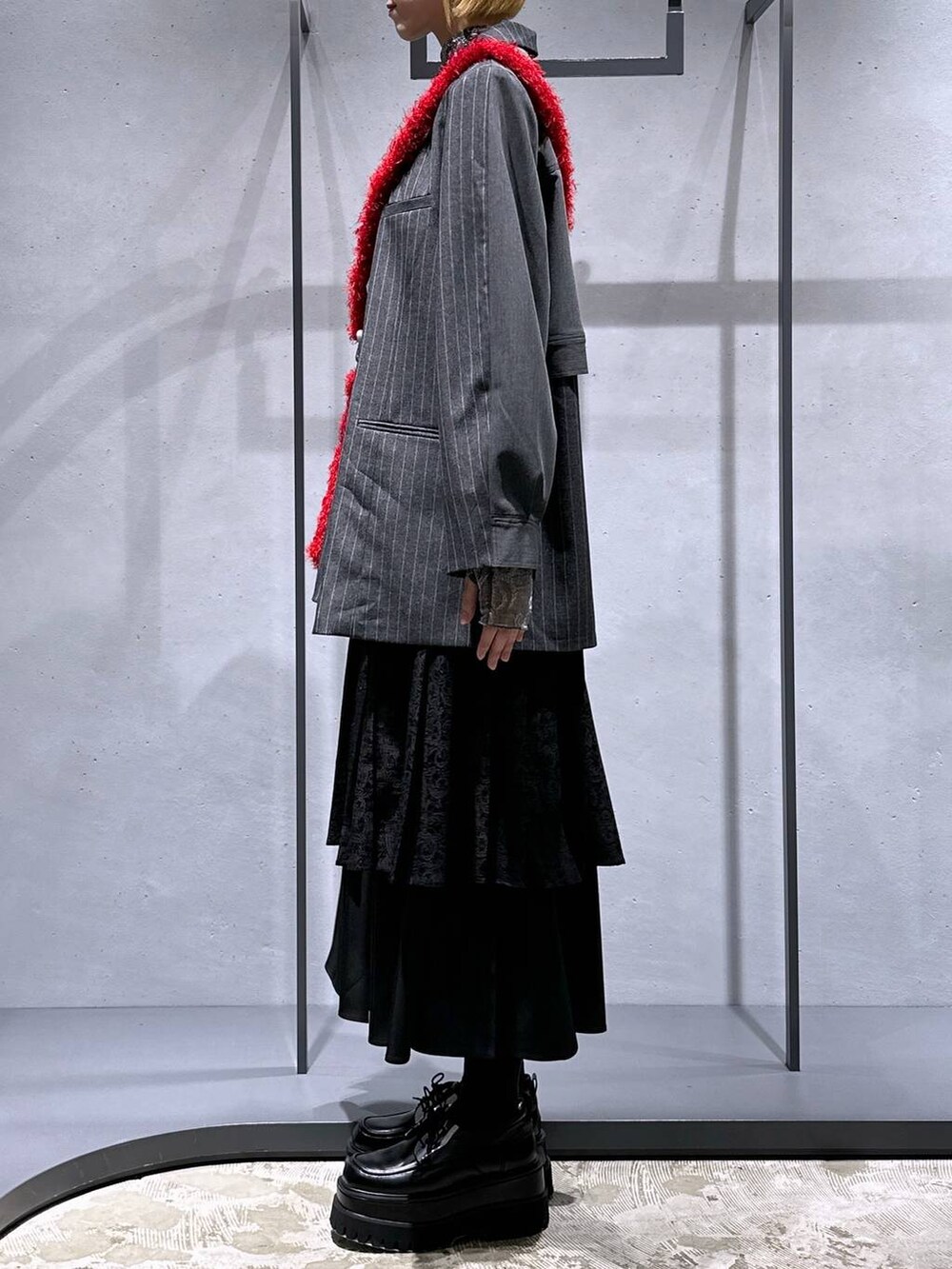 ブラック系のスカート、レッド系のショルダーバッグ、ブラック系のドレスシューズを着用したレディースの秋コーディネートの2枚目の写真