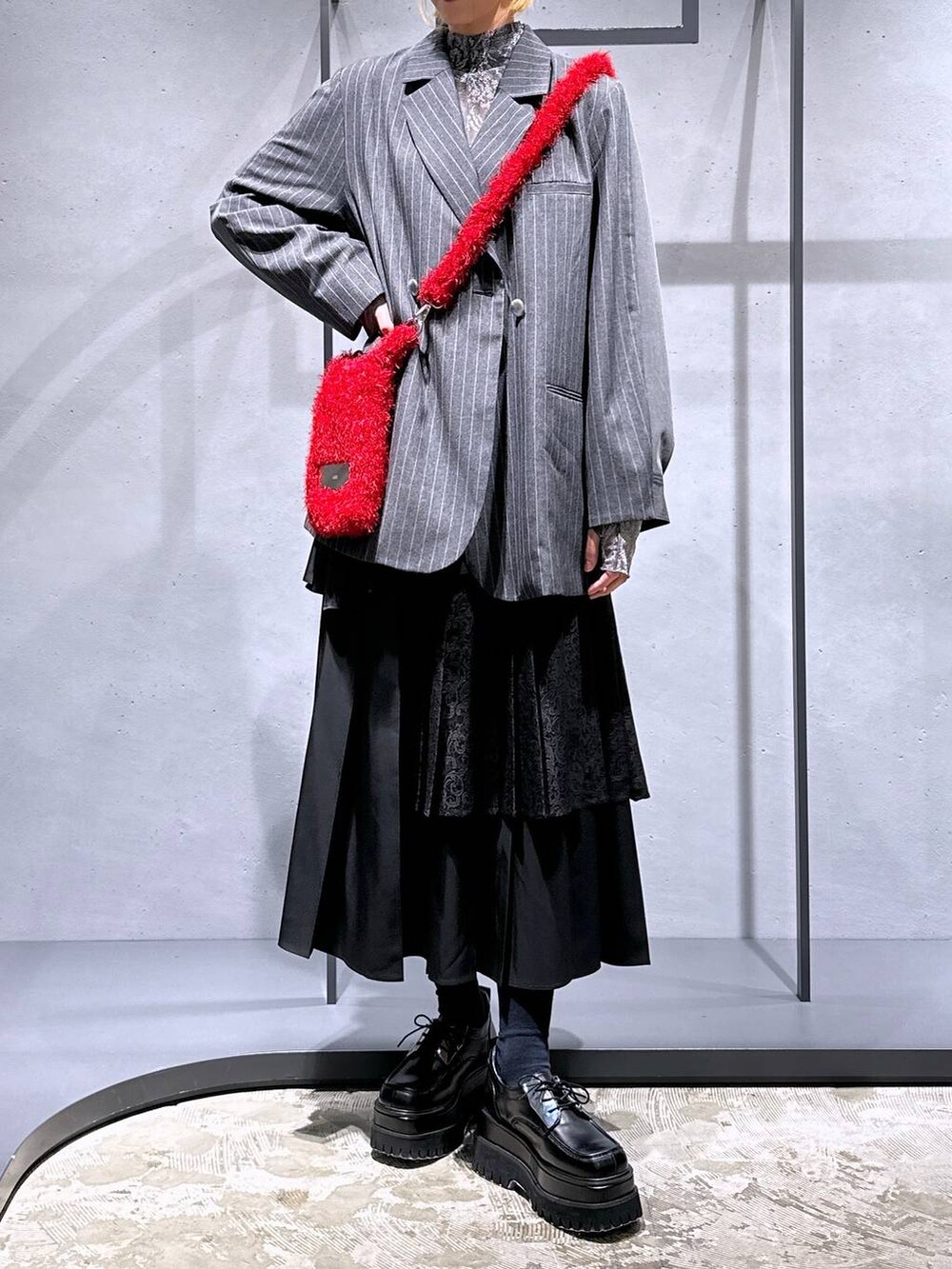 ブラック系のスカート、レッド系のショルダーバッグ、ブラック系のドレスシューズを着用したレディースの秋コーディネートの4枚目の写真