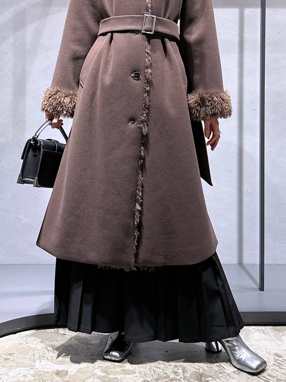 ホワイト系のニット/セーター、シルバー系のブーツ、ブラック系のショルダーバッグを着用したレディースの冬コーディネートの6枚目の写真