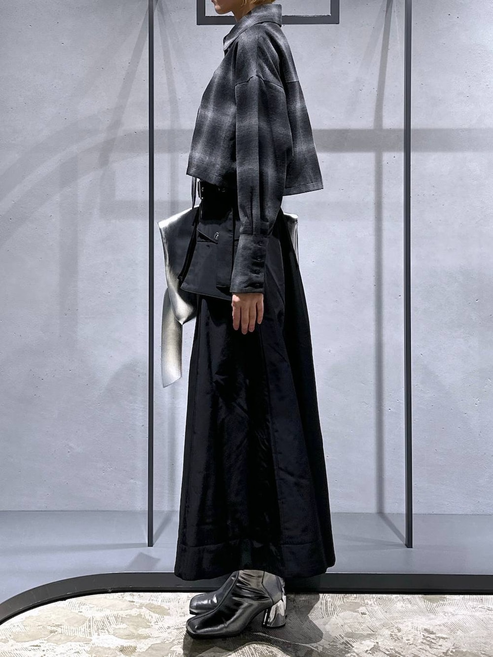 シルバー系のブーツ、ブラック系のスカート、シルバー系のトートバッグを着用したレディースの秋コーディネートの2枚目の写真