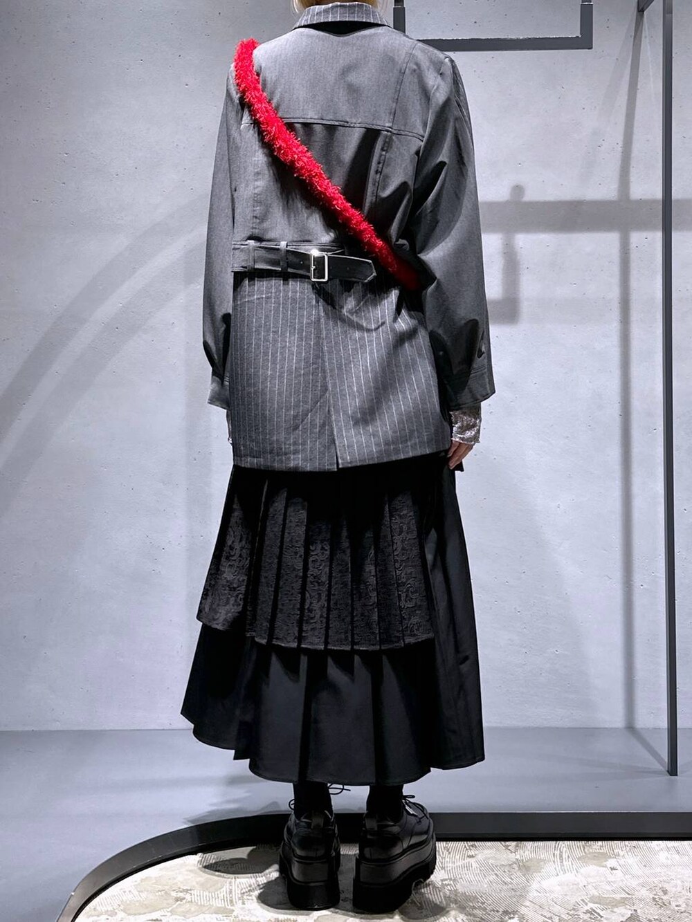 ブラック系のスカート、レッド系のショルダーバッグ、ブラック系のドレスシューズを着用したレディースの秋コーディネートの3枚目の写真