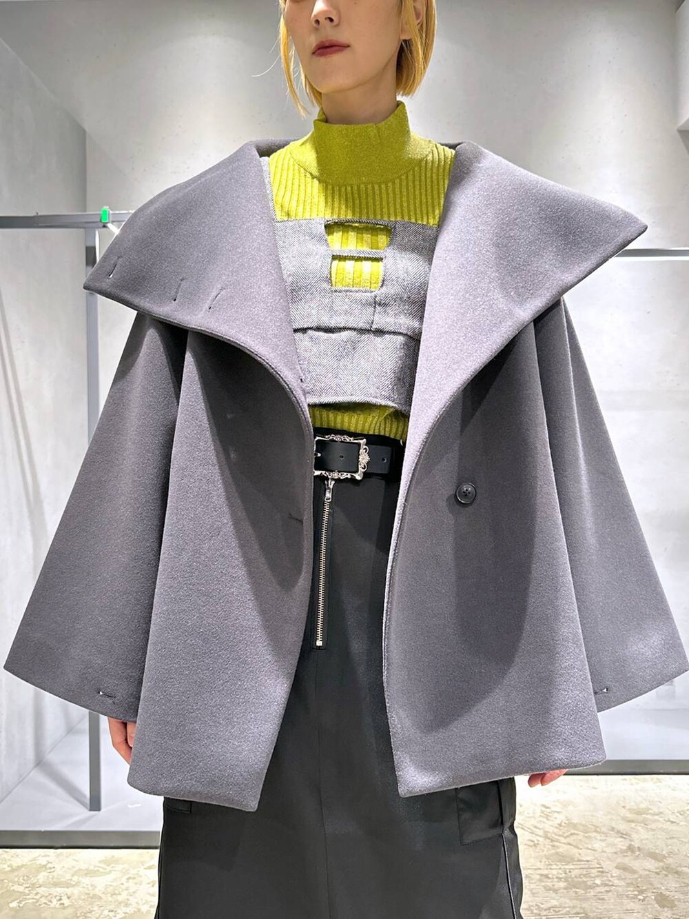 グレー系のチェスターコート、イエロー系のニット/セーター、シルバー系のブーツを着用したレディースの秋コーディネートの5枚目の写真