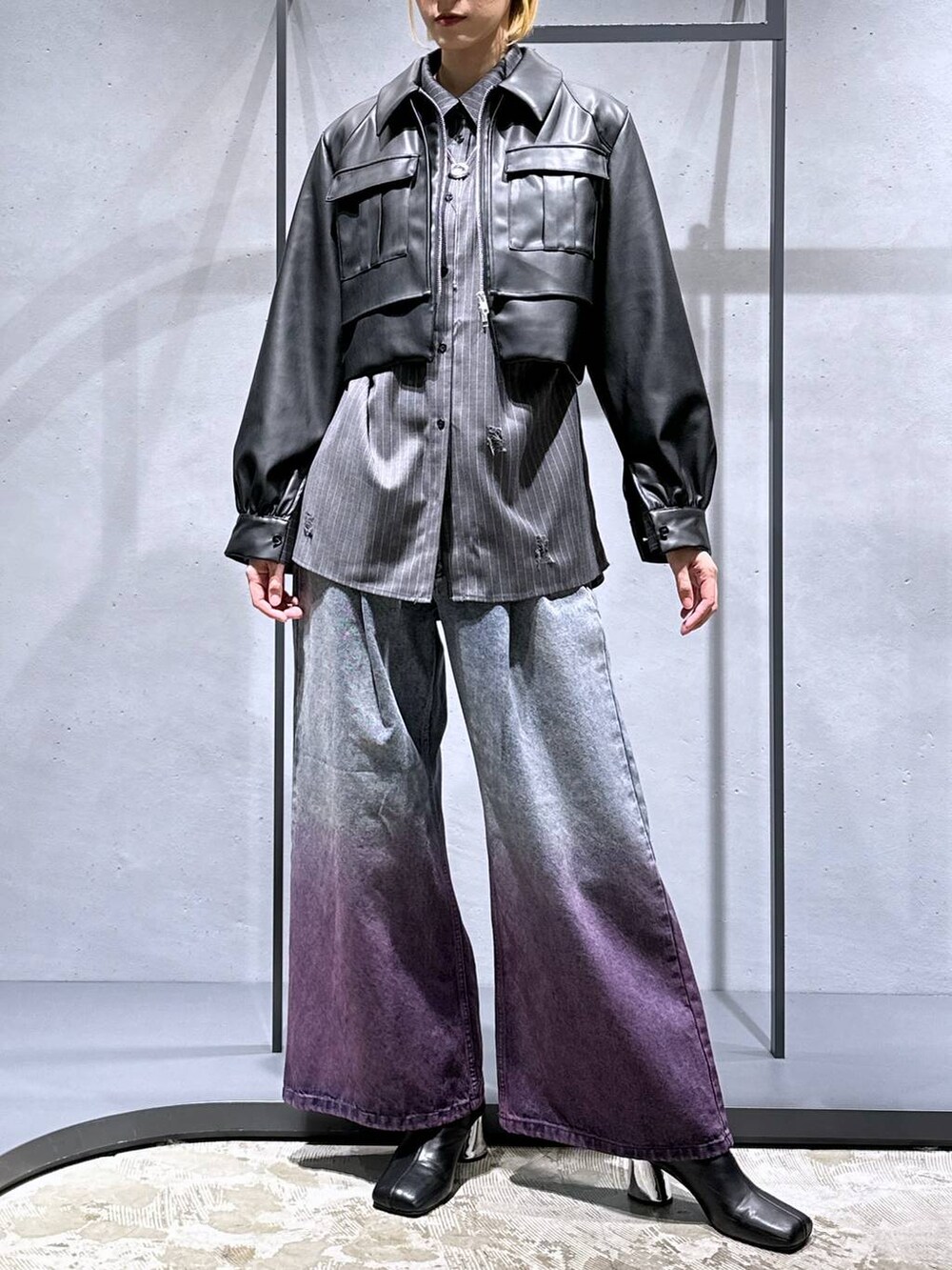 パープル系のデニムパンツ、ブラック系のブーツ、ブラック系のブルゾンを着用したレディースの秋コーディネートの4枚目の写真