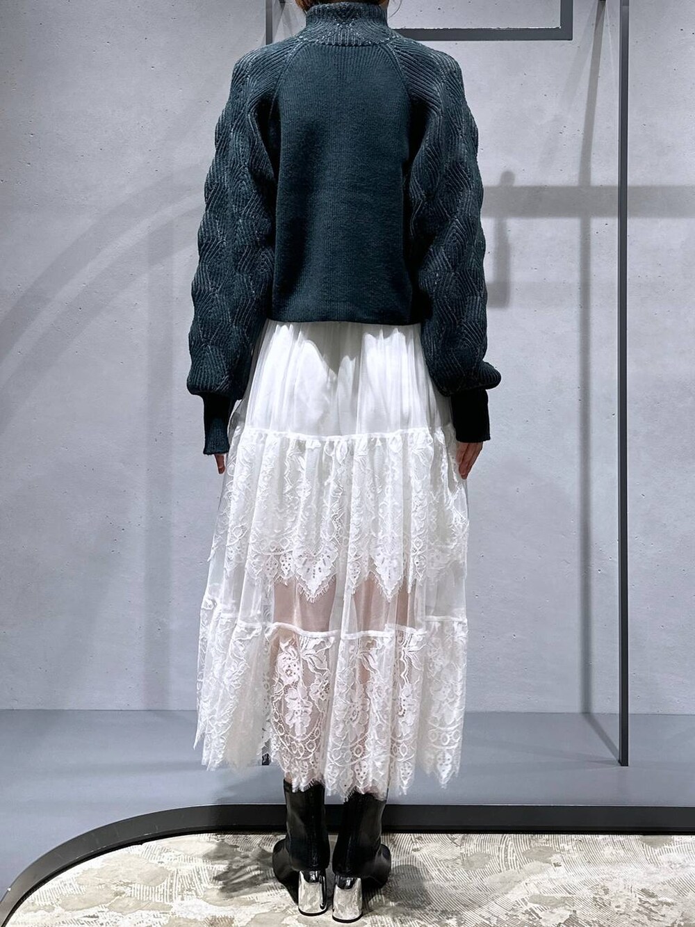 ブラック系のブーツ、グリーン系のカーディガン/ボレロ、ホワイト系のスカートを着用したレディースの秋コーディネートの3枚目の写真