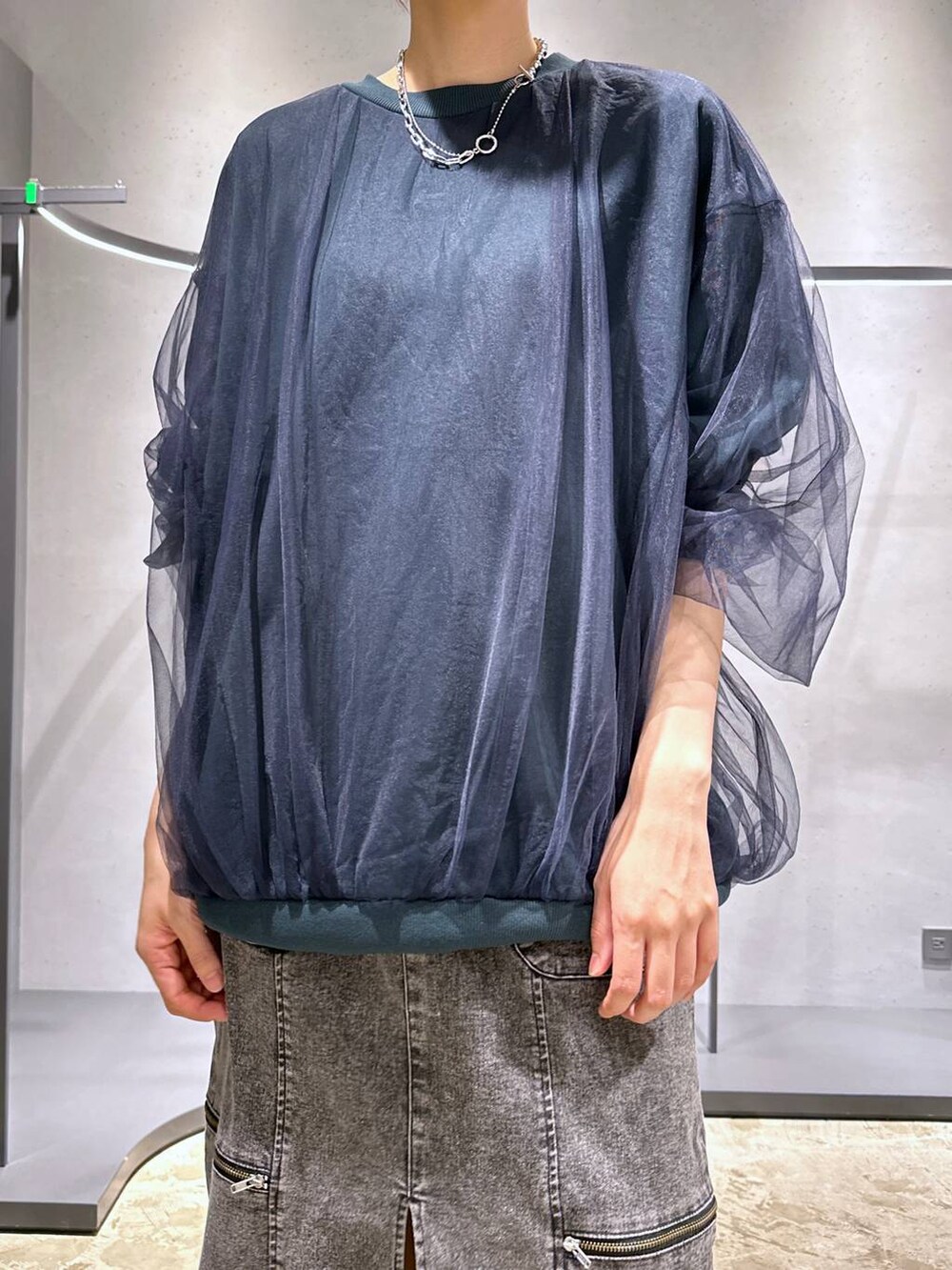 グリーン系のスウェット、ブラック系のブーツ、ブラック系のスカートを着用したレディースの夏コーディネートの5枚目の写真