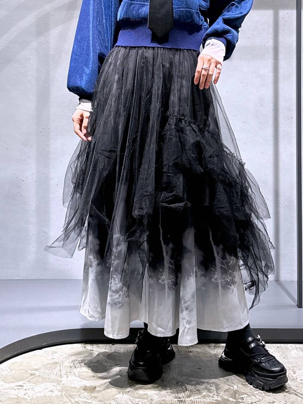 ブラック系のネクタイ、ブルー系のカーディガン/ボレロ、ブラック系のスカートを着用したレディースの冬コーディネートの6枚目の写真