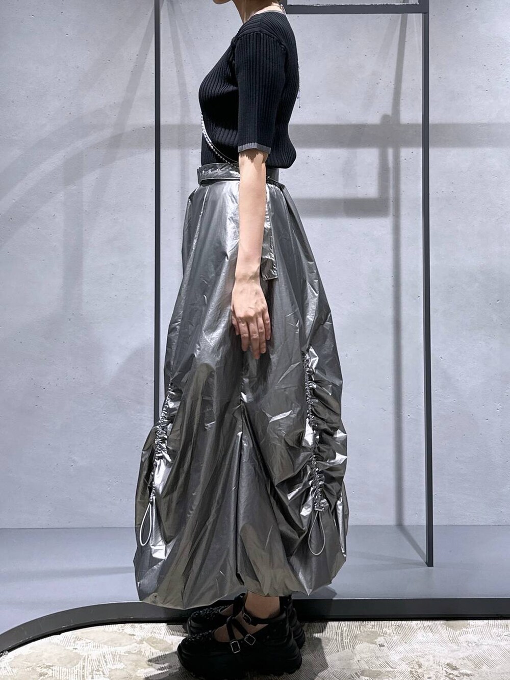 ブラック系のニット/セーター、ブラック系のスニーカー、シルバー系のスカートを着用したレディースの夏コーディネートの2枚目の写真