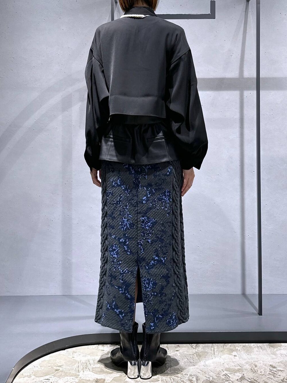 グレー系のスカート、ブラック系のブーツ、ブラック系のシャツ/ブラウスを着用したレディースの秋コーディネートの3枚目の写真