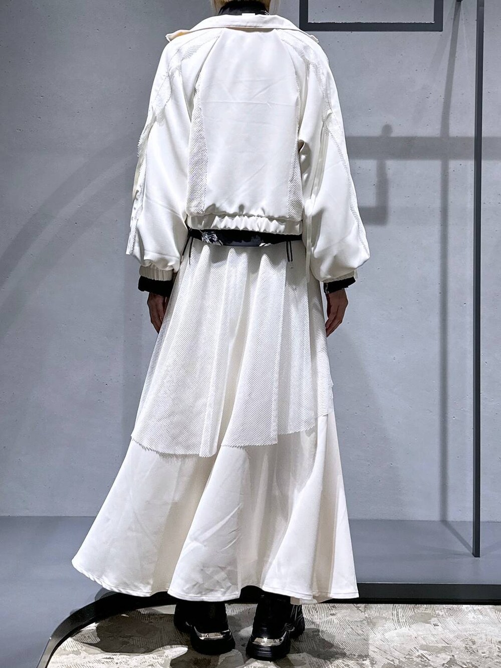 ブラック系のスニーカー、ホワイト系のブルゾン、ホワイト系のスカートを着用したレディースの冬コーディネートの3枚目の写真