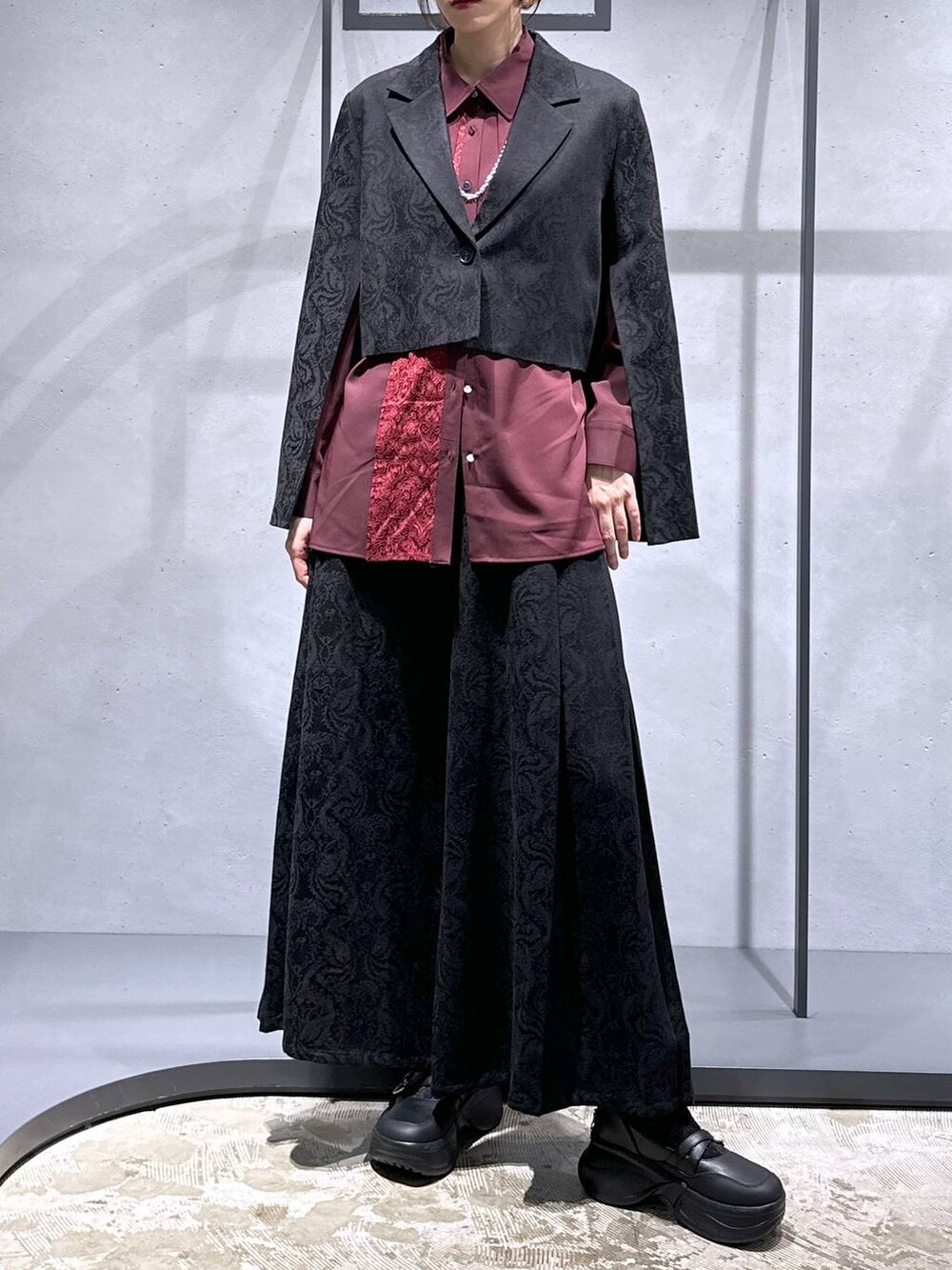 ブラック系のブーツ、ブラック系のテーラードジャケット、レッド系のシャツ/ブラウスを着用したレディースの秋コーディネートの4枚目の写真