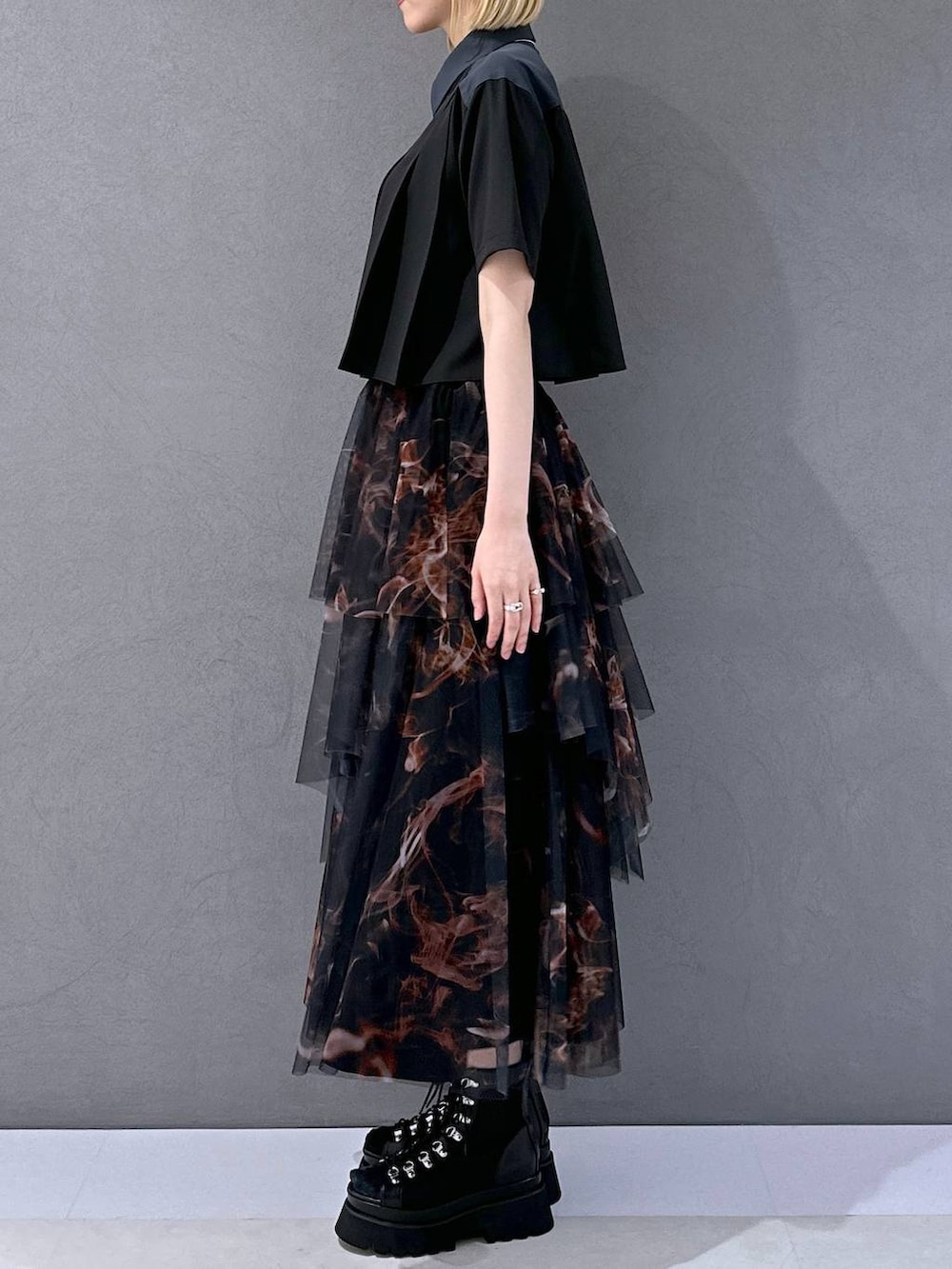 ブラック系のサンダル、オレンジ系のスカート、ブラック系のシャツ/ブラウスを着用したレディースの夏コーディネートの2枚目の写真