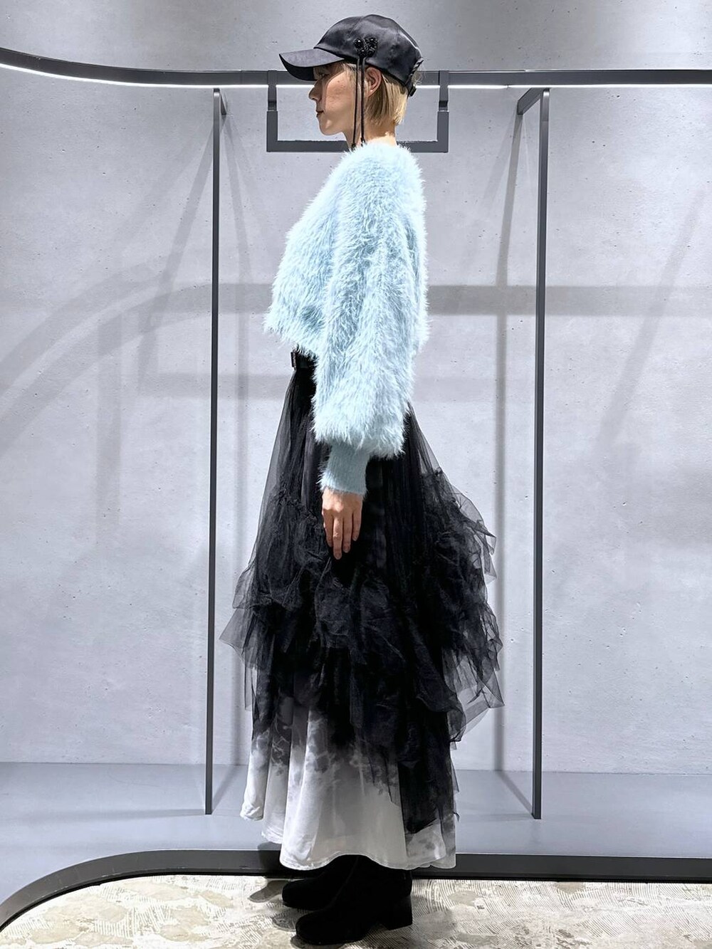 グリーン系のニット/セーター、ブラック系のブーツ、ブラック系のスカートを着用したレディースの冬コーディネートの2枚目の写真