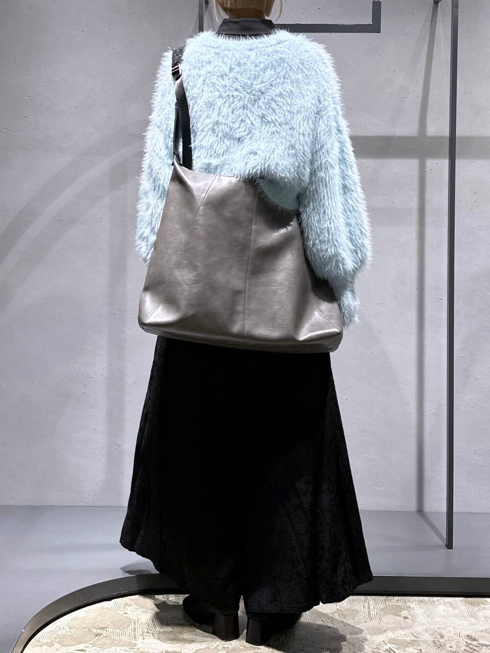 グリーン系のニット/セーター、ブラック系のブーツ、ブルー系のシャツ/ブラウスを着用したレディースの冬コーディネートの3枚目の写真