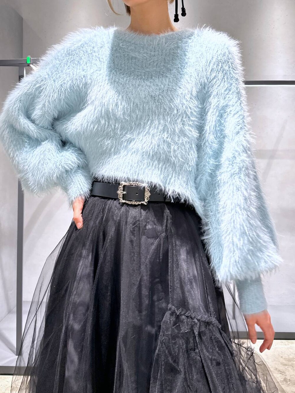 グリーン系のニット/セーター、ブラック系のブーツ、ブラック系のスカートを着用したレディースの冬コーディネートの5枚目の写真