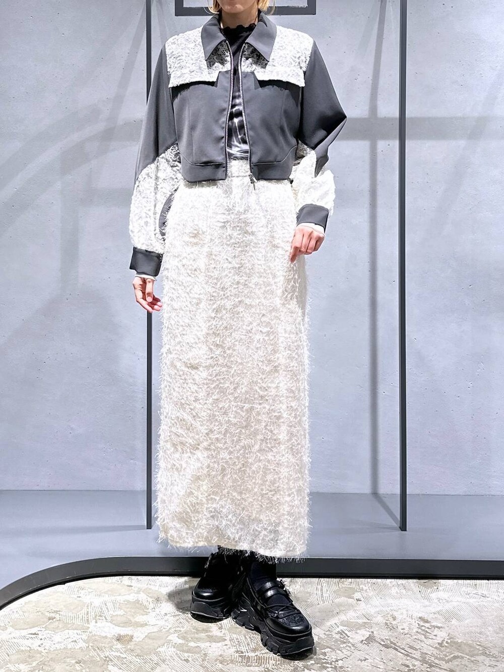 ブラック系のTシャツ/カットソー、ブラック系のスニーカー、ホワイト系のスカートを着用したレディースの冬コーディネートの4枚目の写真