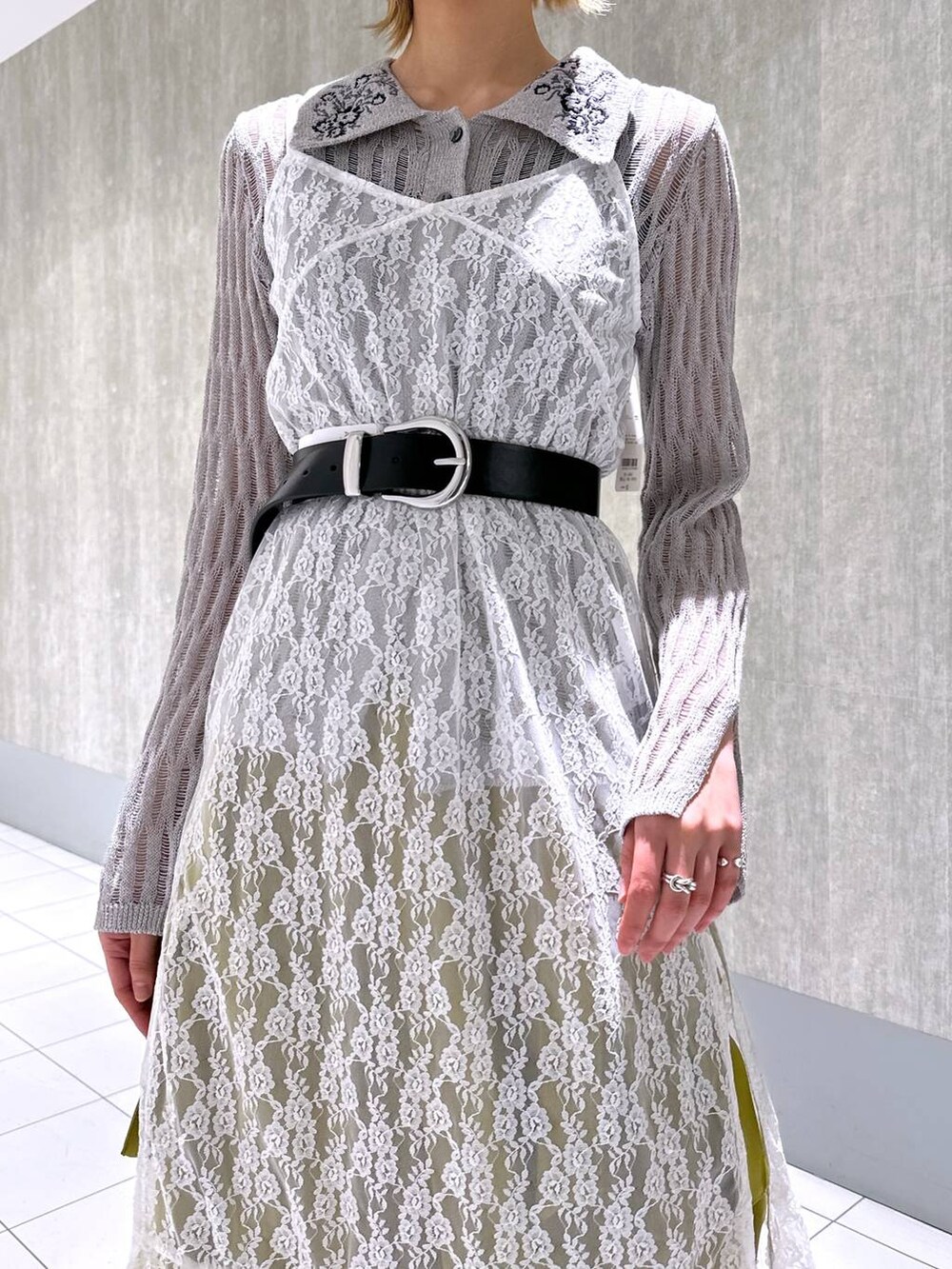 イエロー系のカーゴパンツ、グレー系のニット/セーター、ホワイト系のワンピースを着用したレディースの春コーディネートの5枚目の写真