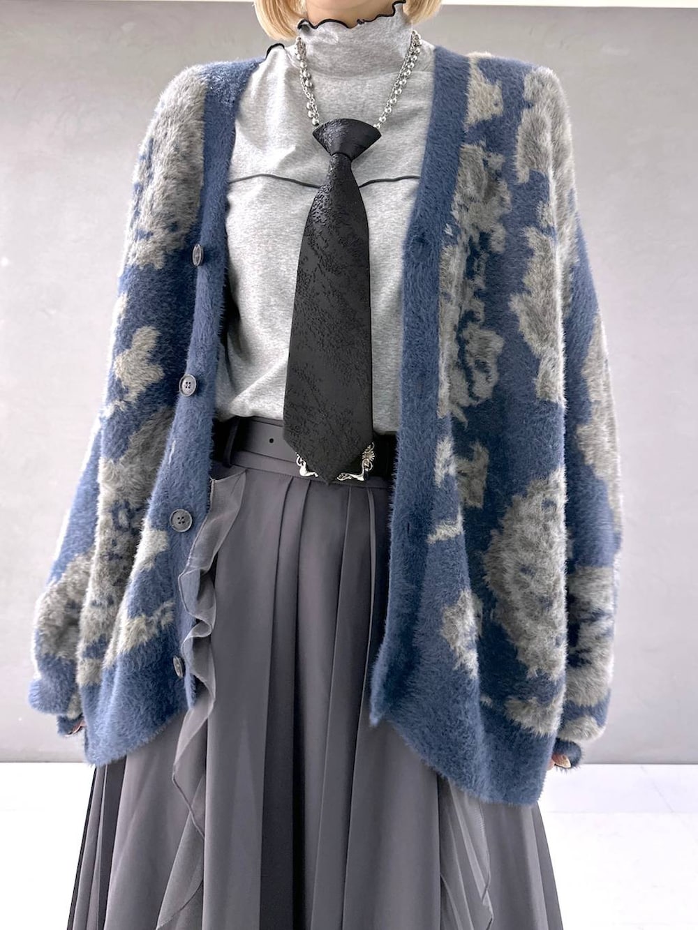 ブラック系のネクタイ、ブルー系のカーディガン/ボレロ、ブラック系のブーツを着用したレディースの秋コーディネートの5枚目の写真