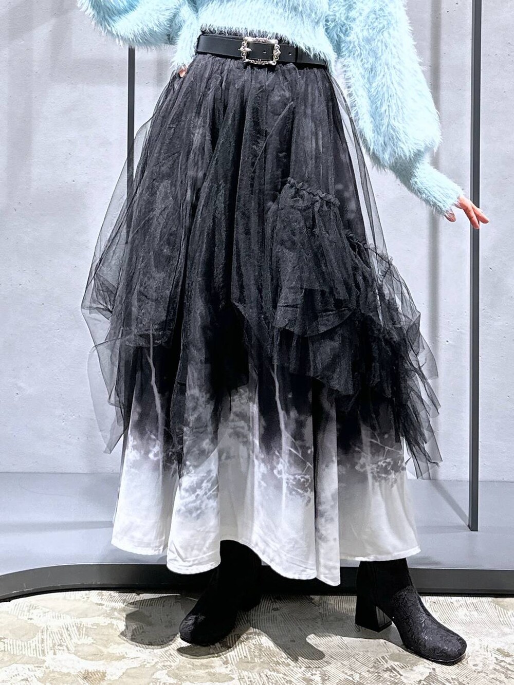 グリーン系のニット/セーター、ブラック系のブーツ、ブラック系のスカートを着用したレディースの冬コーディネートの6枚目の写真