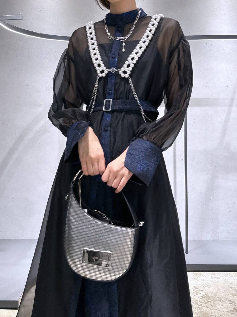 シルバー系のハンドバッグ、ブラック系のブーツ、ブルー系のドレスを着用したレディースの秋コーディネートの5枚目の写真