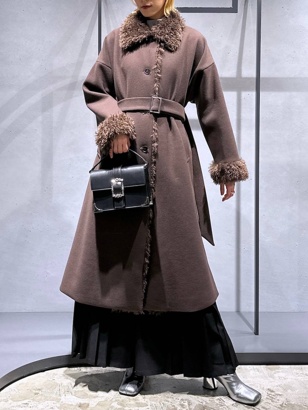 ホワイト系のニット/セーター、シルバー系のブーツ、ブラック系のショルダーバッグを着用したレディースの冬コーディネートの4枚目の写真