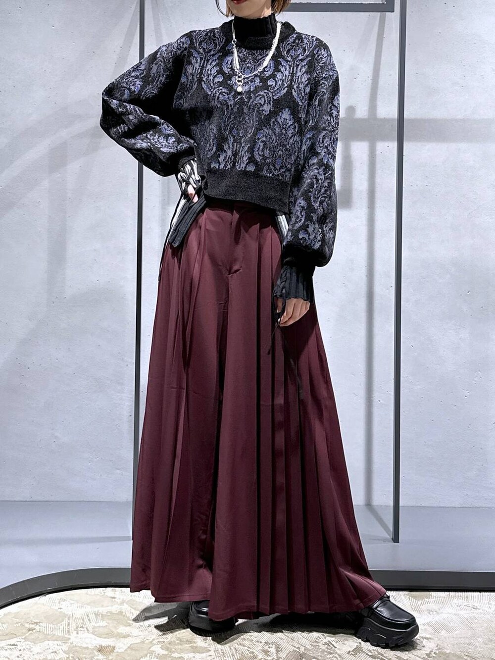 ブラック系のニット/セーター、ブラック系のローファー、レッド系のその他パンツを着用したレディースの秋コーディネートの4枚目の写真