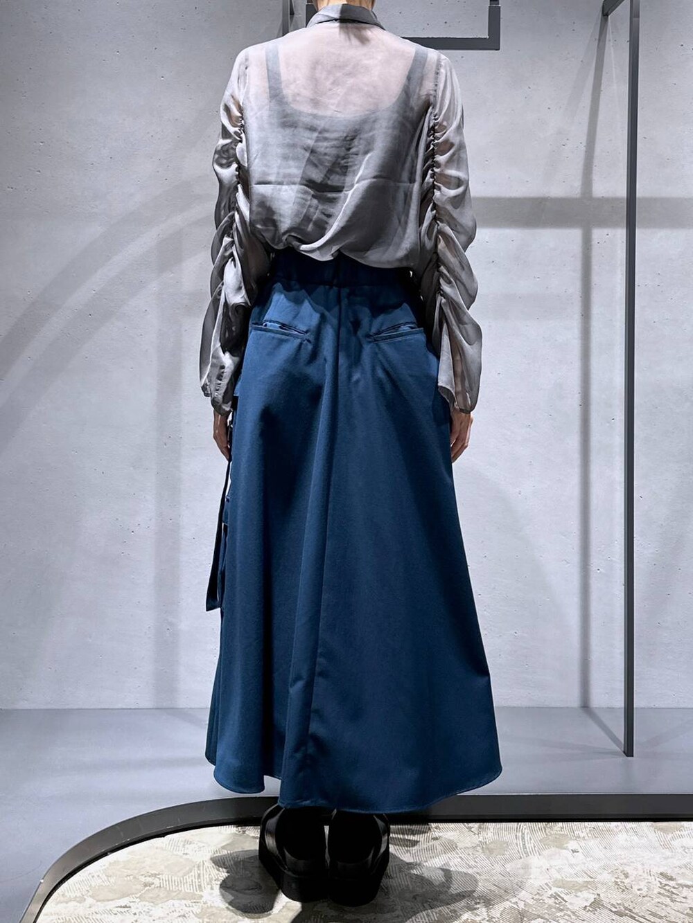 ブラック系のサンダル、ブルー系のスカート、シルバー系のネックレスを着用したレディースの春コーディネートの3枚目の写真