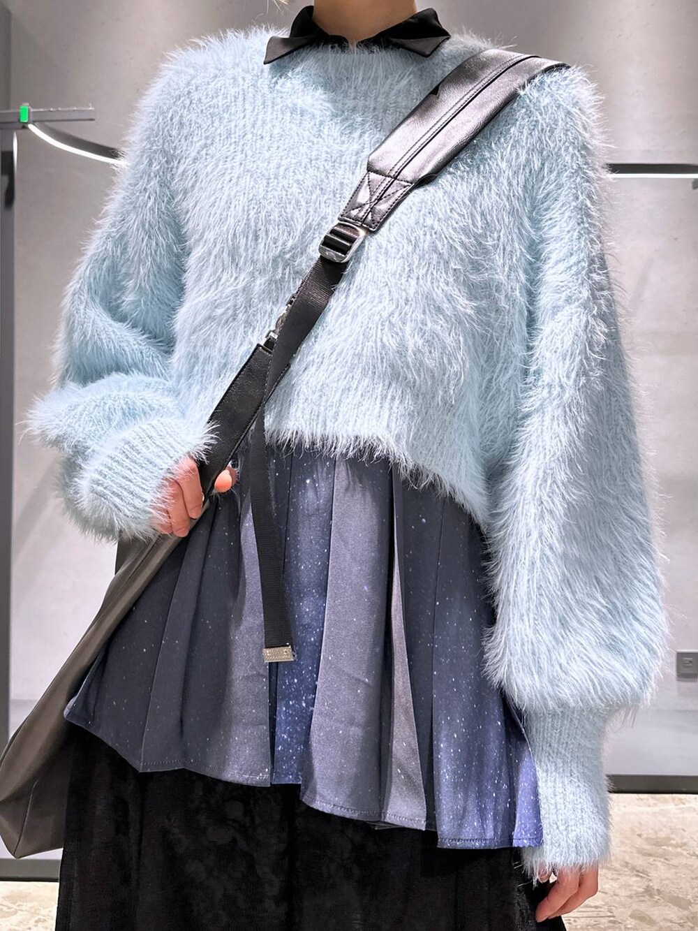 グリーン系のニット/セーター、ブラック系のブーツ、ブルー系のシャツ/ブラウスを着用したレディースの冬コーディネートの5枚目の写真