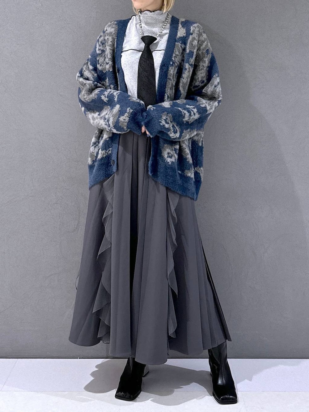 ブラック系のネクタイ、ブルー系のカーディガン/ボレロ、ブラック系のブーツを着用したレディースの秋コーディネートの4枚目の写真