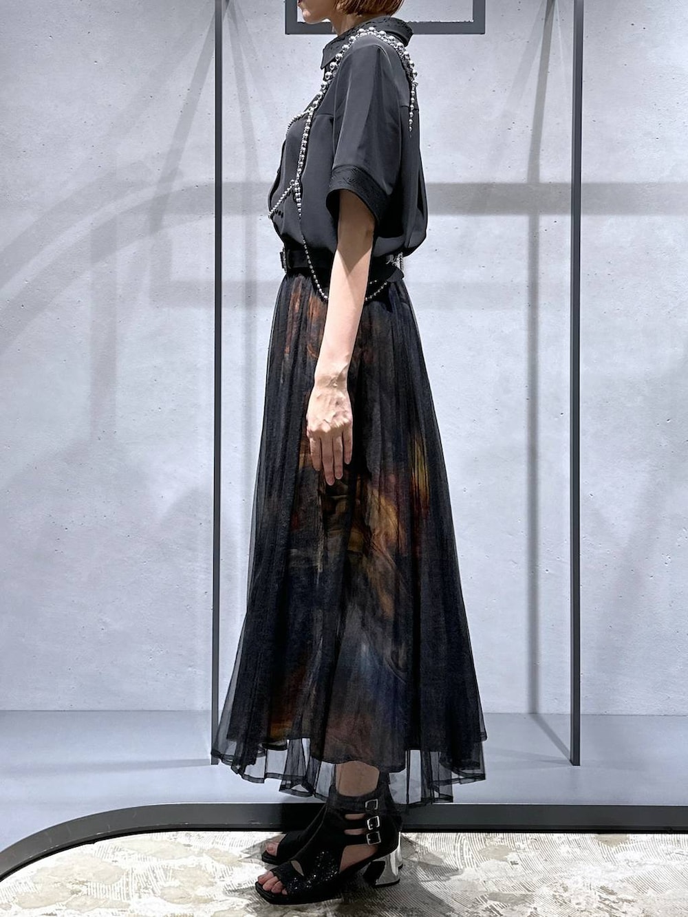 ブラック系のシャツ/ブラウス、ブラック系のサンダル、オレンジ系のスカートを着用したレディースの夏コーディネートの2枚目の写真