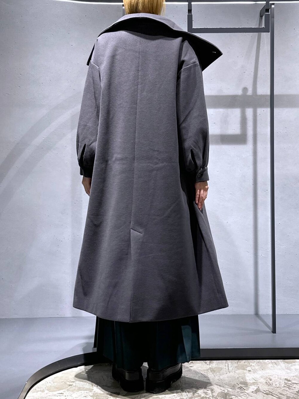 グレー系のチェスターコート、ブラック系のニット/セーター、グリーン系のシャツ/ブラウスを着用したレディースの秋コーディネートの3枚目の写真