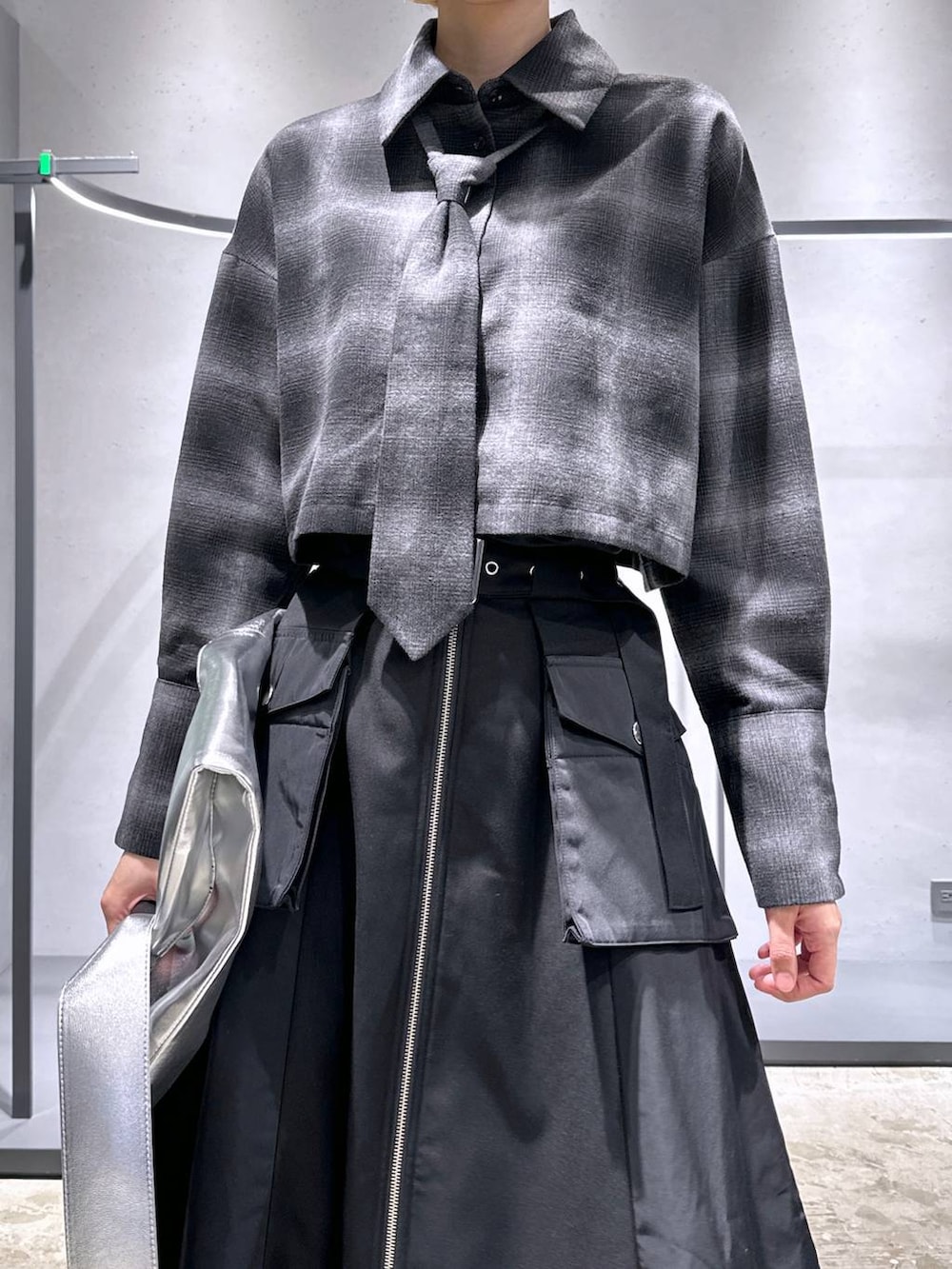 シルバー系のブーツ、ブラック系のスカート、シルバー系のトートバッグを着用したレディースの秋コーディネートの5枚目の写真