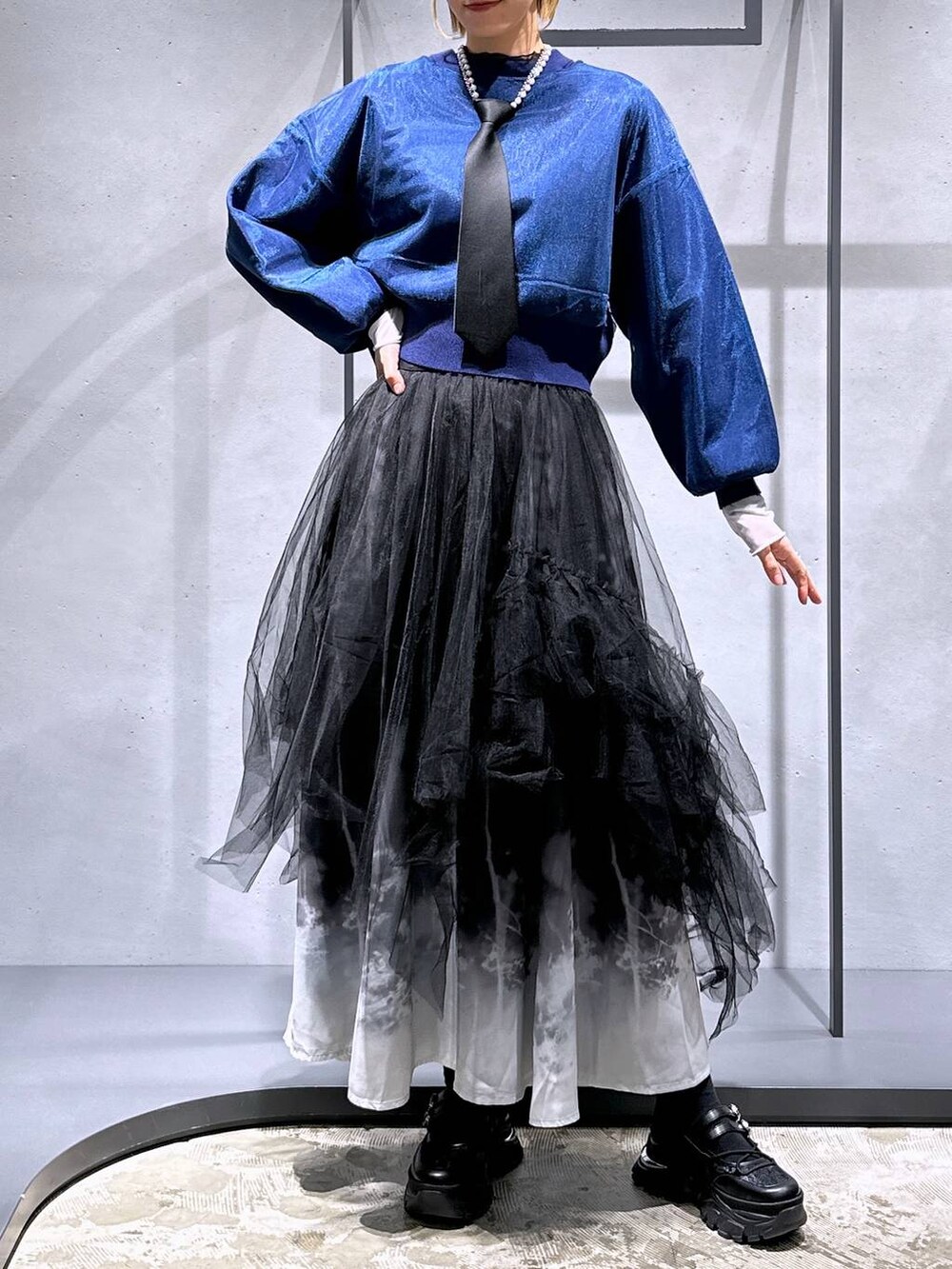 ブラック系のネクタイ、ブルー系のカーディガン/ボレロ、ブラック系のスカートを着用したレディースの冬コーディネートの4枚目の写真