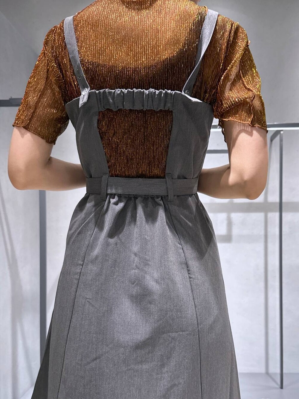 シルバー系のサンダル、オレンジ系のTシャツ/カットソー、グレー系のジャンパースカートを着用したレディースの夏コーディネートの3枚目の写真