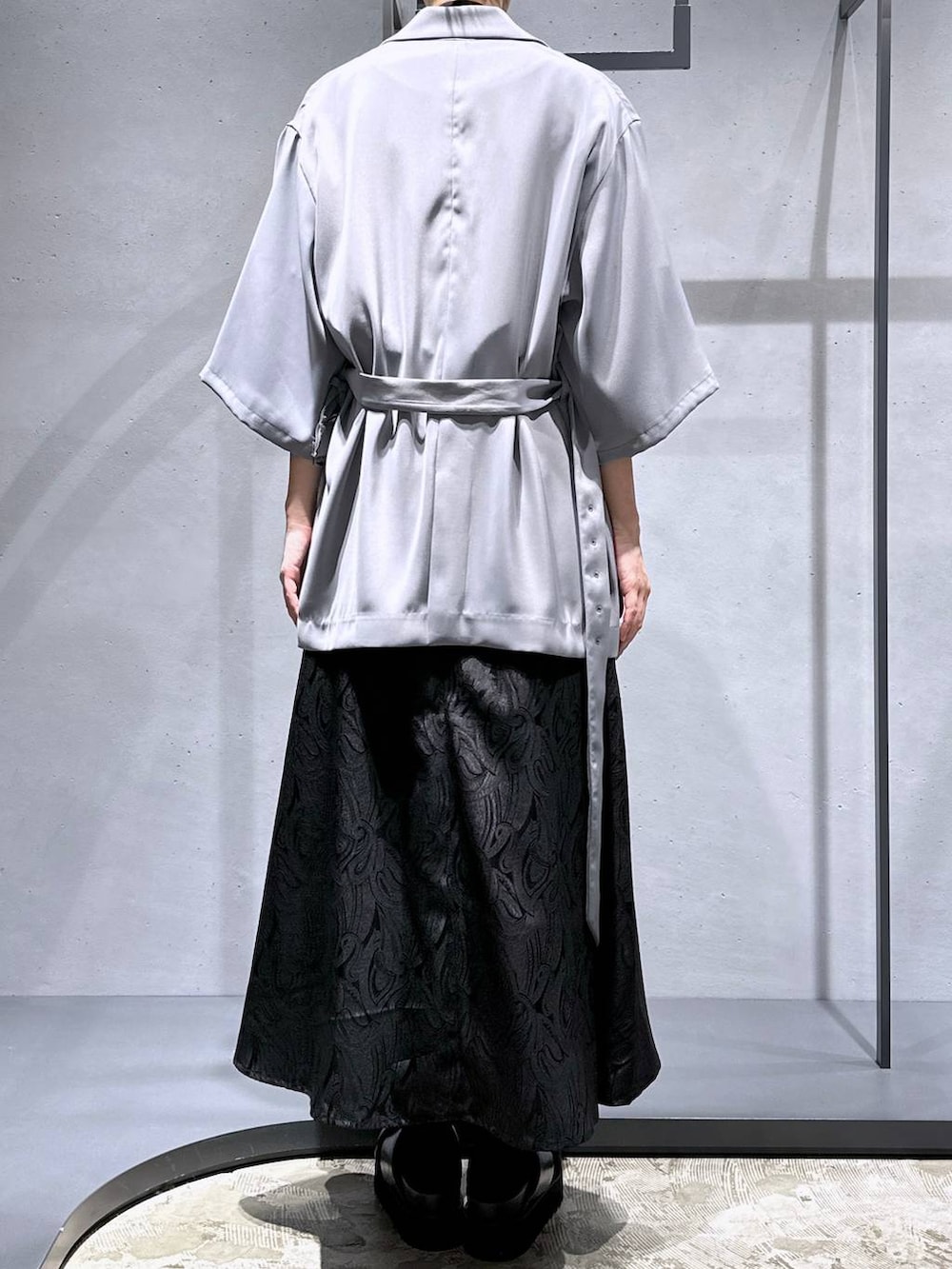 ブラック系のサンダル、ブラック系のスカート、グレー系のテーラードジャケットを着用したレディースの春コーディネートの3枚目の写真