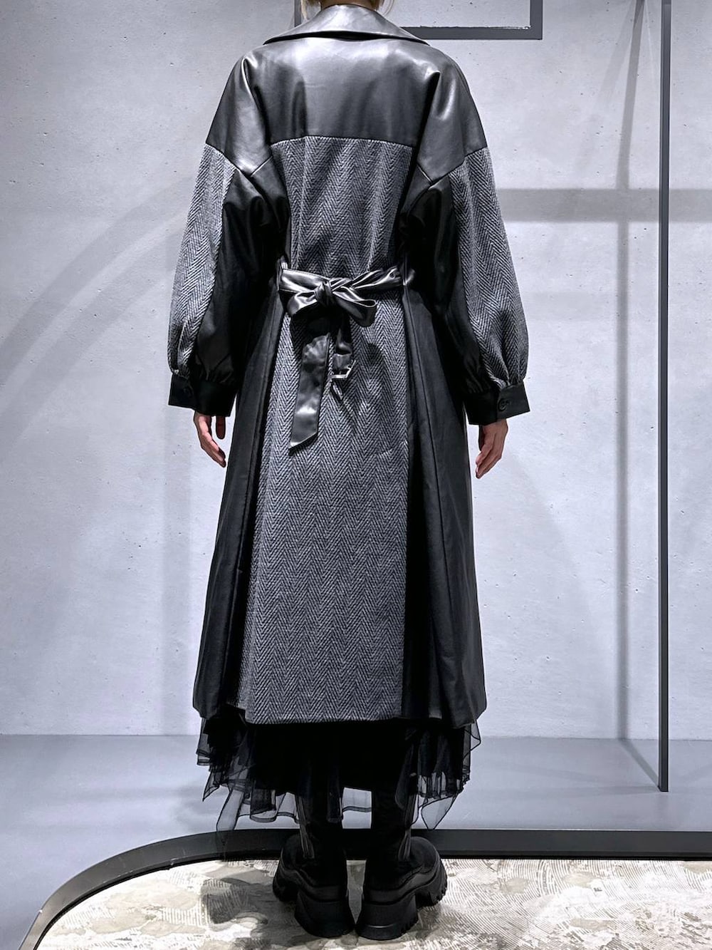 グレー系のチェスターコート、レッド系のニット/セーター、ブラック系のブーツを着用したレディースの冬コーディネートの3枚目の写真